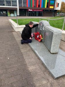 Picture of student laying poppies down on the war memorial
