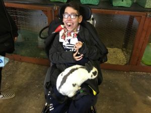 student holding a rabbit on his lap in animal care